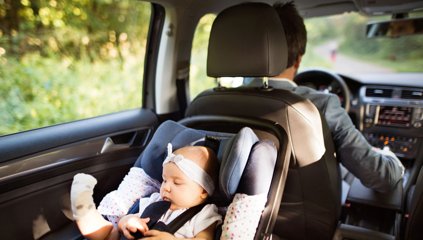 Barn som sitter i en bilbarnstol i baks&auml;tet p&aring; en bil.