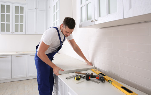 Hantverkare monterar en bänkskiva i ett kök.