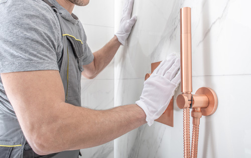 Hantverkare monterar en dusch i ett badrum.